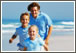 Family of three wearing baby blue shirts runnin on beach